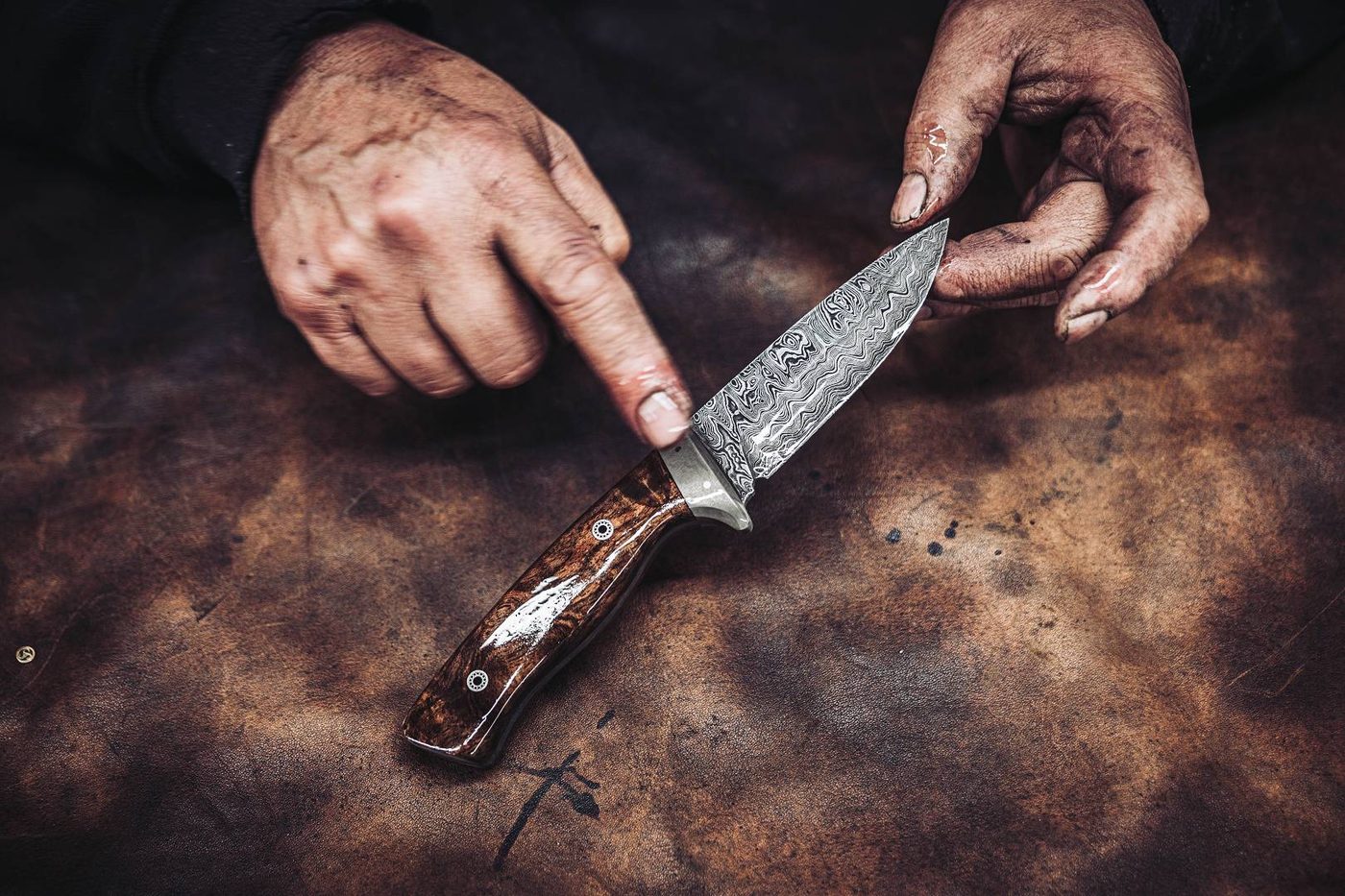 Schmiedeh&auml;nde halten ein fertiges Damastmesser