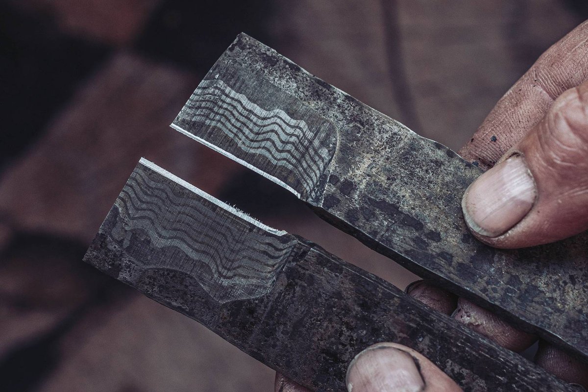 Angeschliffenes Damaststahl-Stueck zeigt echte Lagenstruktur im Schleiftest