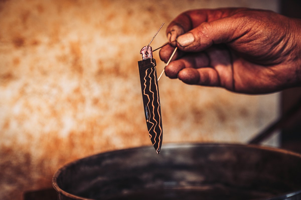 Wurmrot-Klinge wird nach dem Aetzbad gehalten und das Kupfer-Damast-Muster wird sichtbar