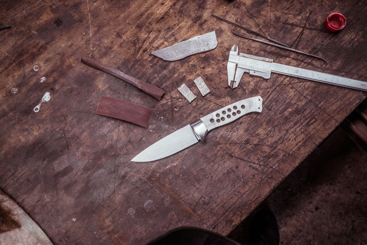Messerklinge aus Damaststahl neben Schieblehre und Griffmaterial auf der Werkbank