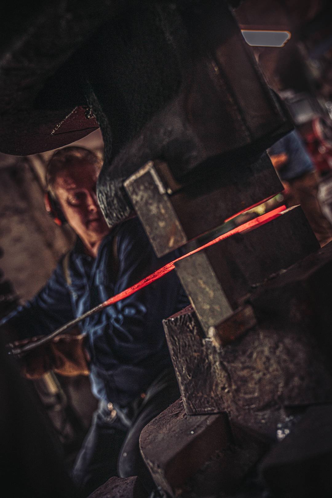 Schmied bearbeitet gl&uuml;henden Stahl am Federhammer in der Moorschmied-Werkstatt