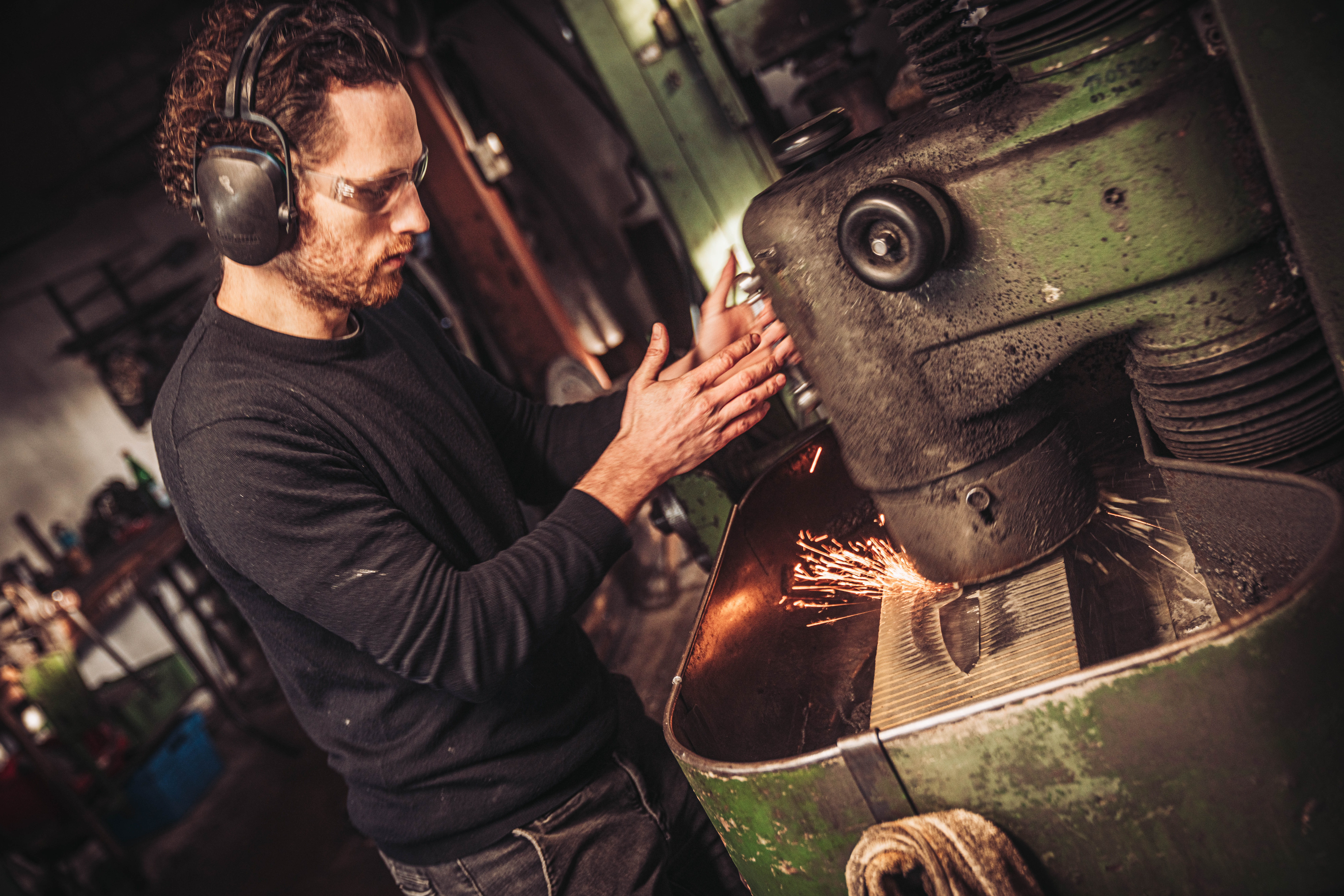 Konzentriertes Schleifen an der Topfschleifmaschine &mdash; Funken spr&uuml;hen, volle Aufmerksamkeit auf die Klinge