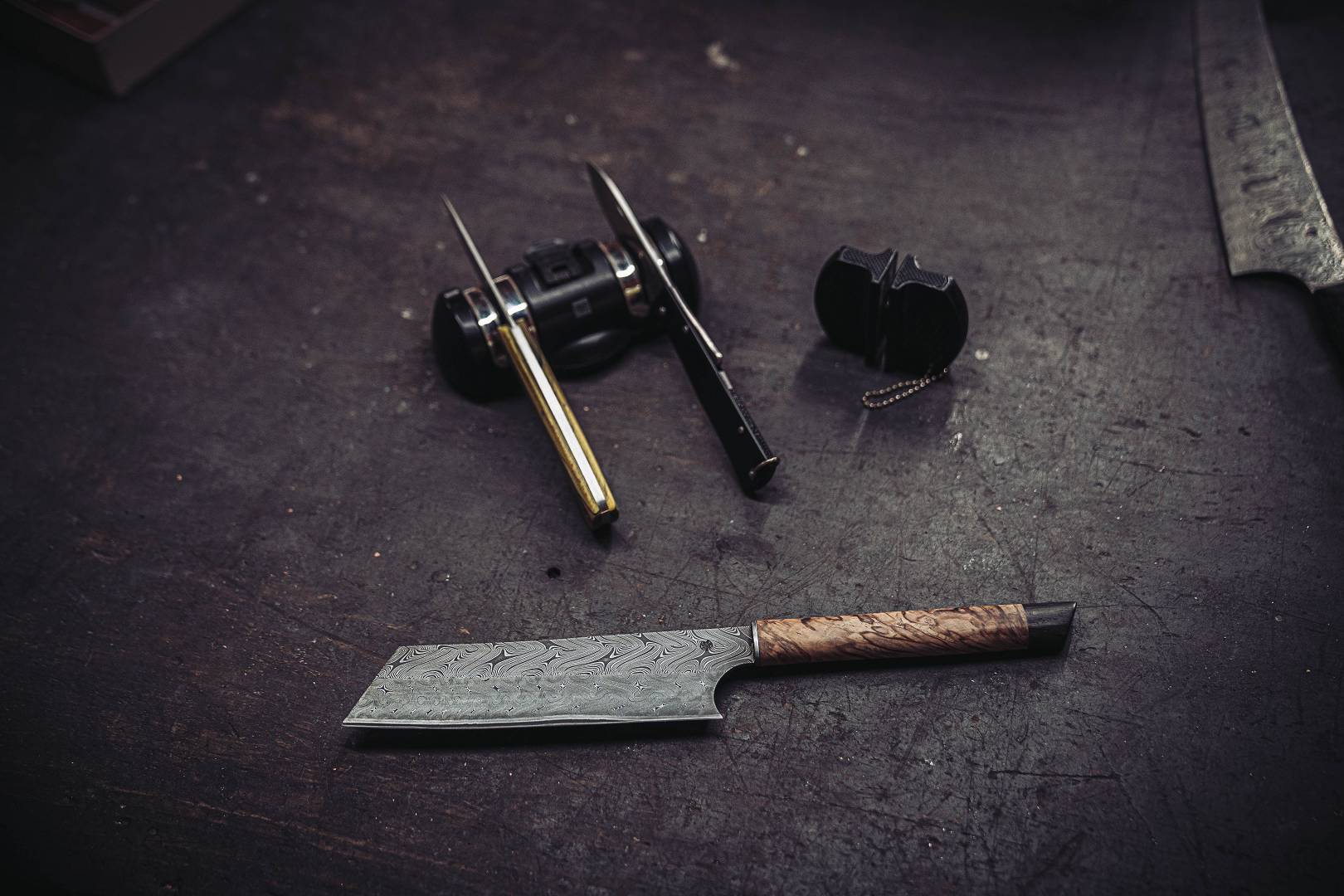 Fertiges Damastmesser mit Griffschalen aus Maserbirke auf der Werkbank