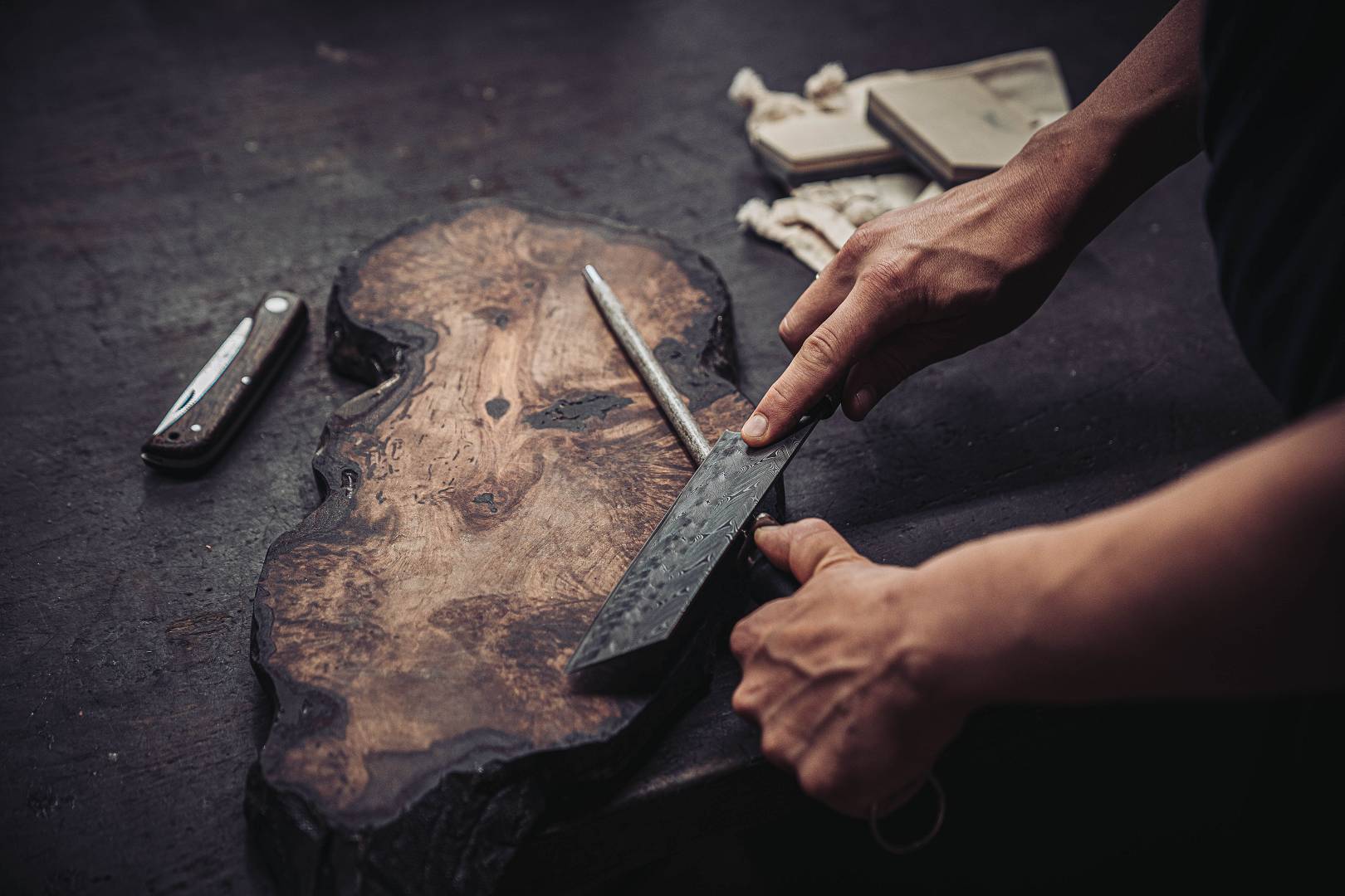 Damastmesser mit verschiedenen Griffmaterialien auf einer Holzscheibe in der Moorschmiede