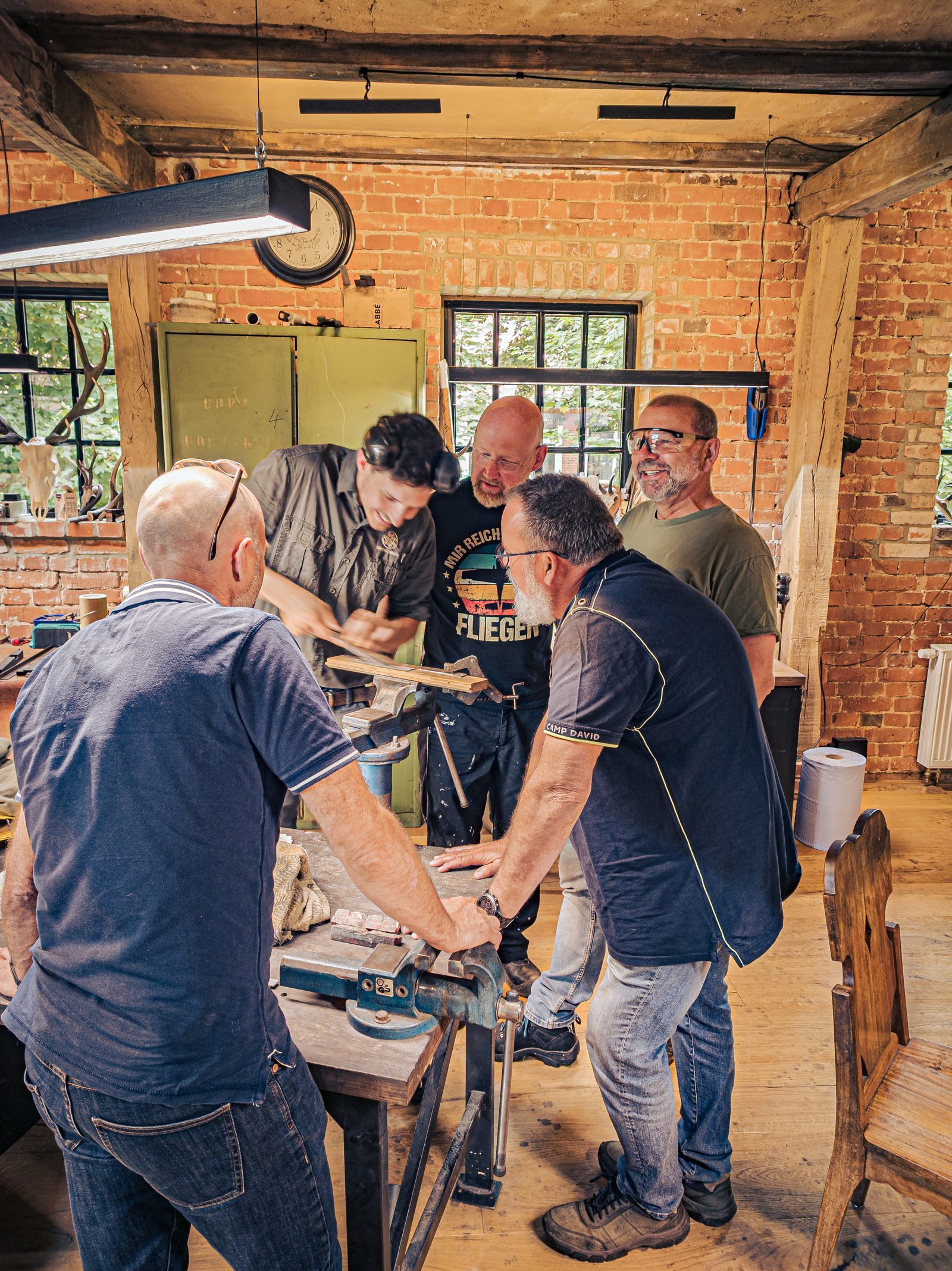 F&uuml;nf Kursteilnehmer beim konzentrierten Arbeiten in der Schmiede-Werkstatt