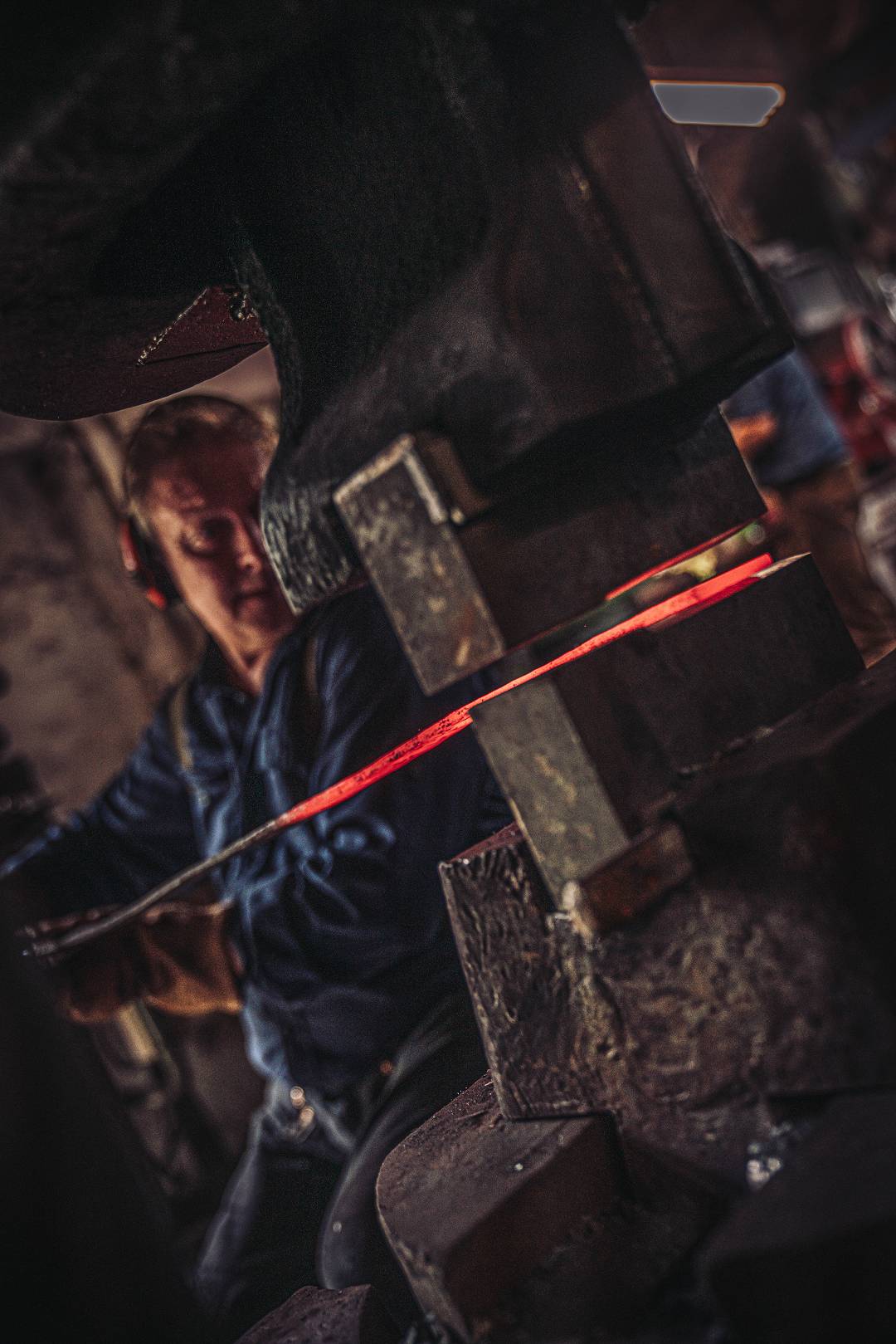 Schmied mit gl&uuml;hendem Stahl am Federhammer in der Moorschmiede