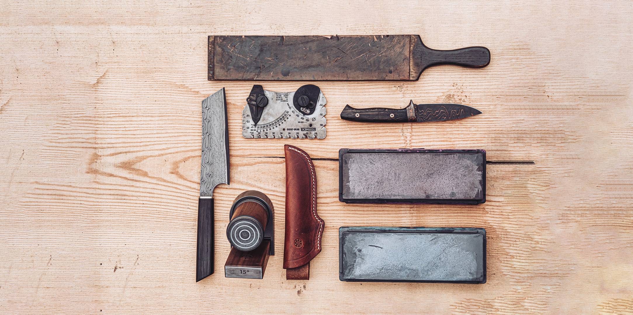 Verschiedene handgeschmiedete Messer und Werkzeug auf einer Arbeitsfl&auml;che