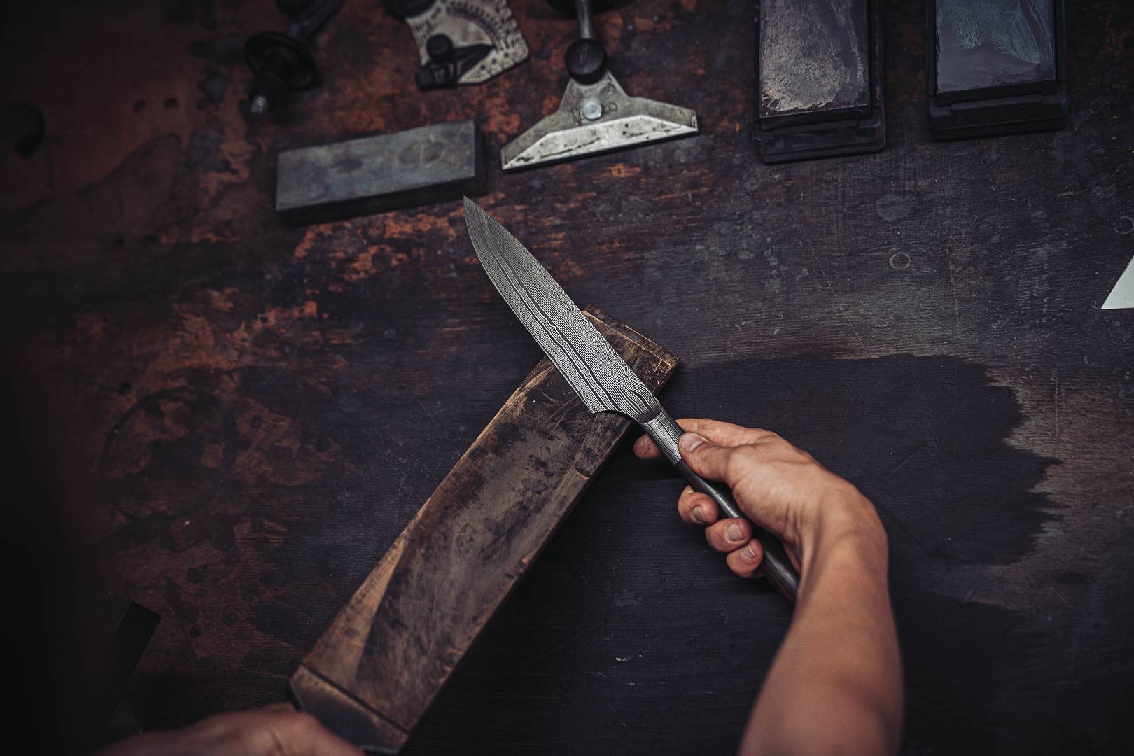Spitze Damastklinge in der Hand gehalten &mdash; klassische Jagdmesser-Geometrie mit schlanker Spitze